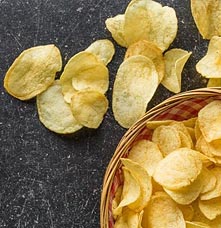 A basket of chips, with some scattered across the table.
